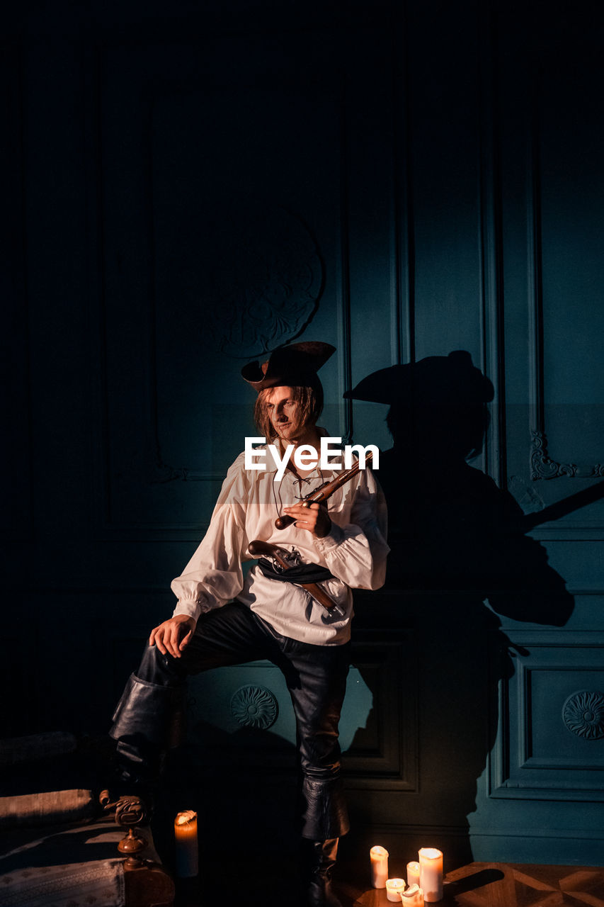 FULL LENGTH OF A WOMAN SITTING IN ILLUMINATED HAT