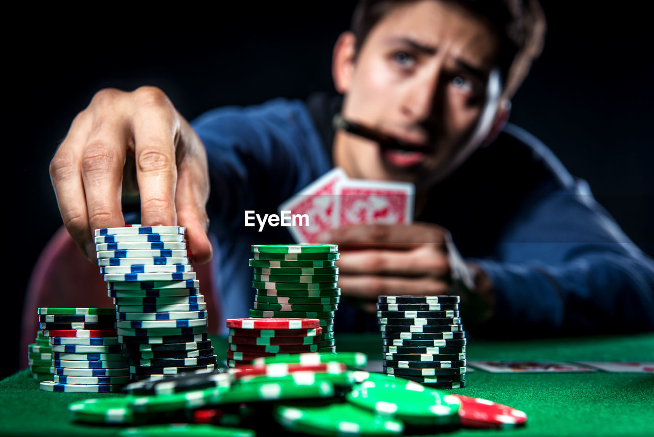 Man playing poker with cigar against black background