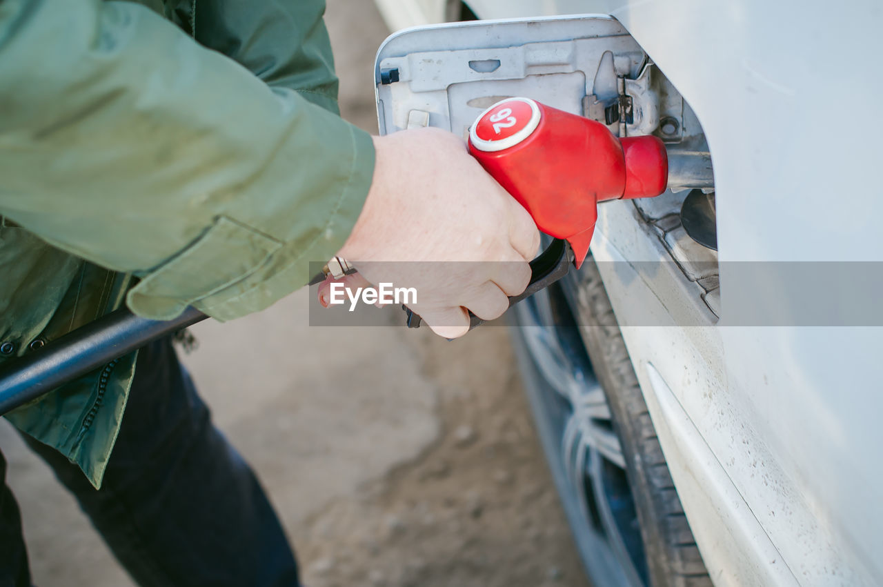 Midsection of man filling fuel in car tank