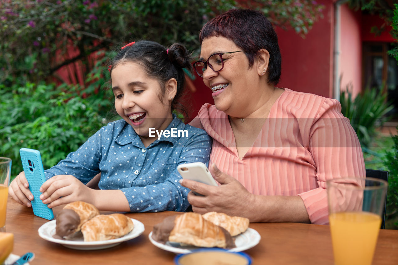 Smiling grandmother and granddaughter looking at laptop