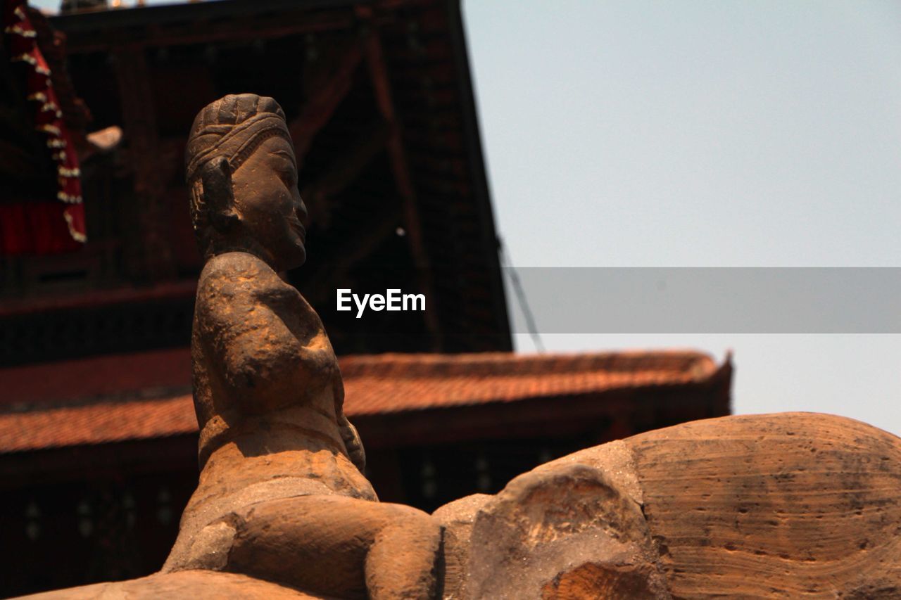 Low angle view of old statue against sky