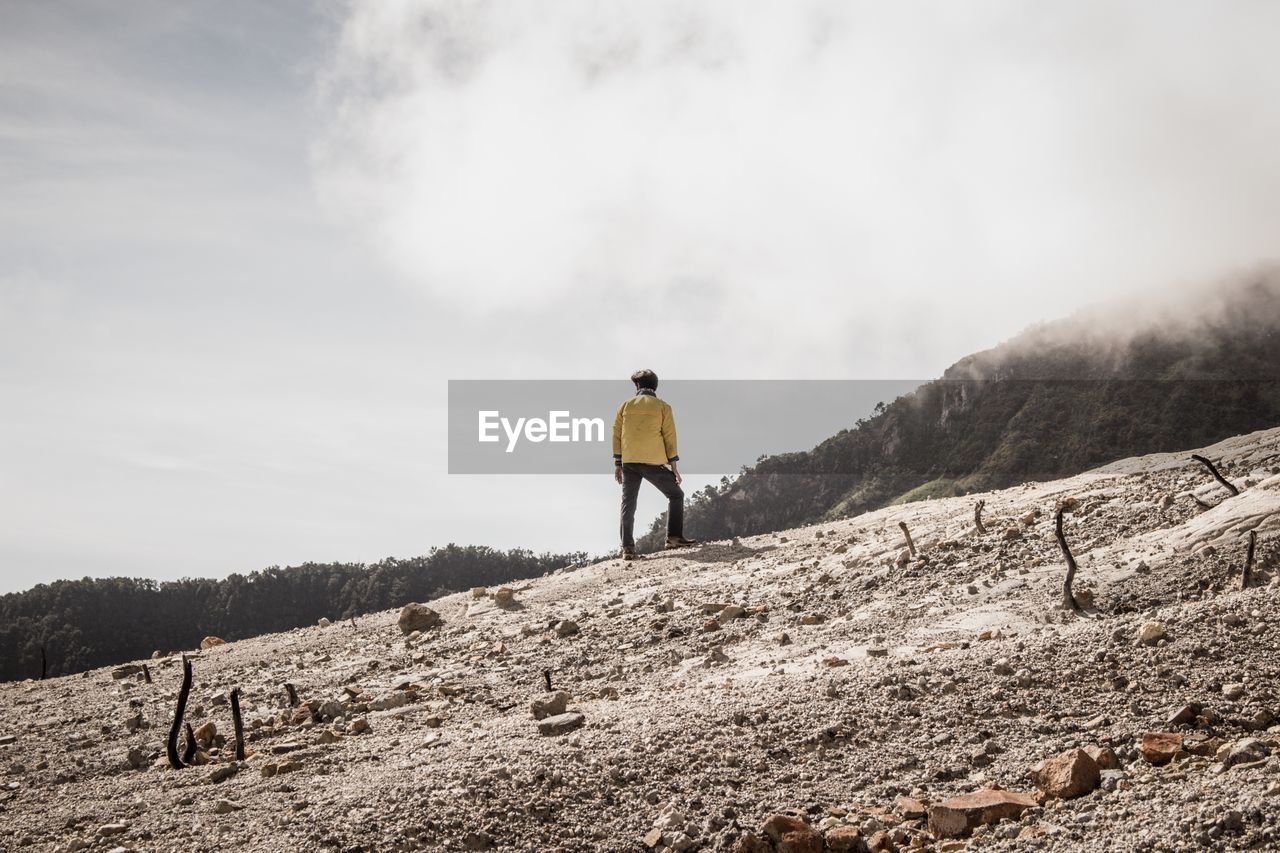 Rear view of man standing on landscape against sky