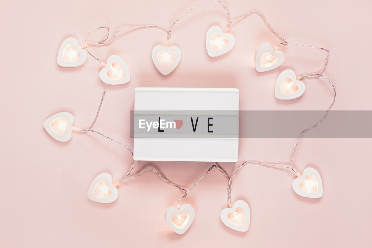 Minimal valentine flat lay with word love on lightboard and heart shape garland. valentine's day 