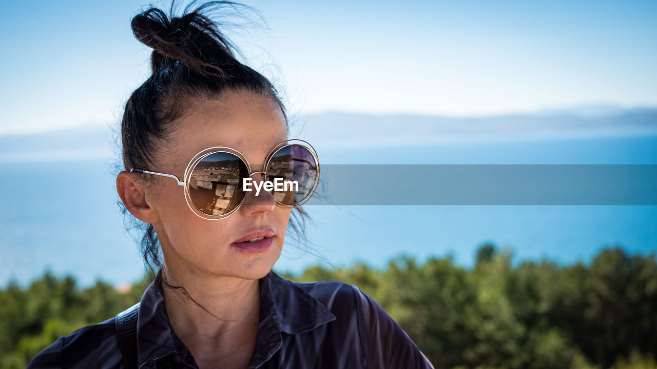 Young woman wearing sunglasses against sky