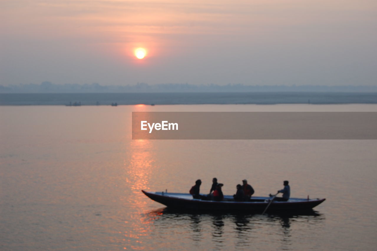 PEOPLE ON BOAT IN SEA DURING SUNSET