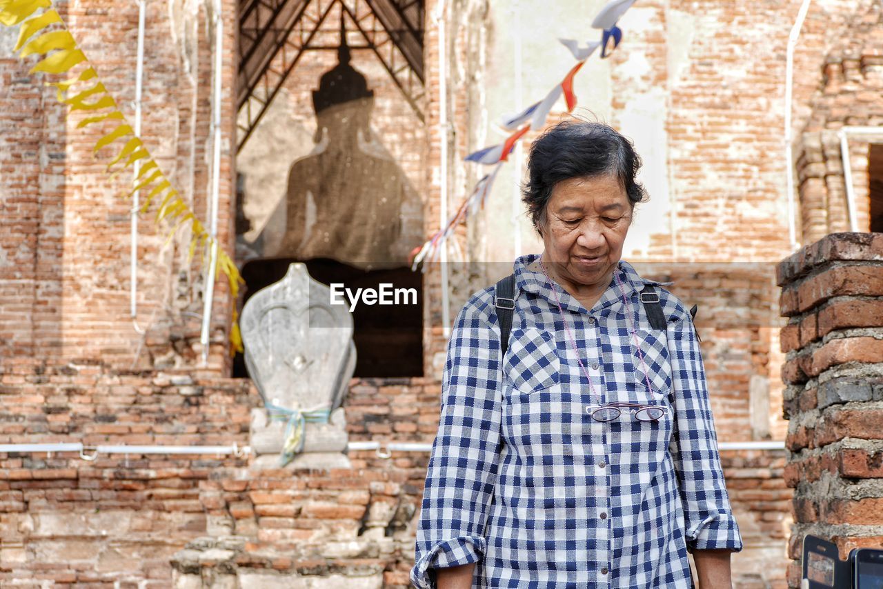 Senior woman standing against old temple