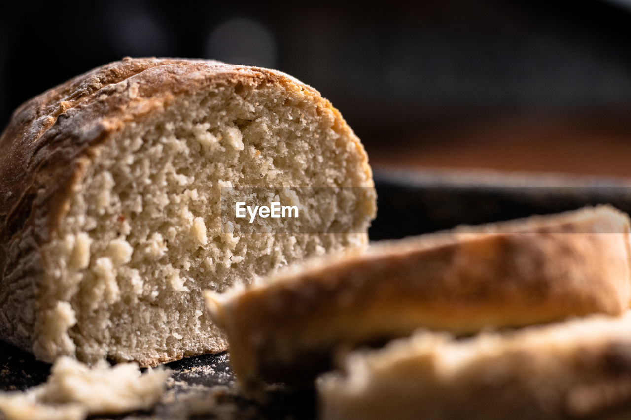 Baked homemade bread on black and wooden background, bakery setting.