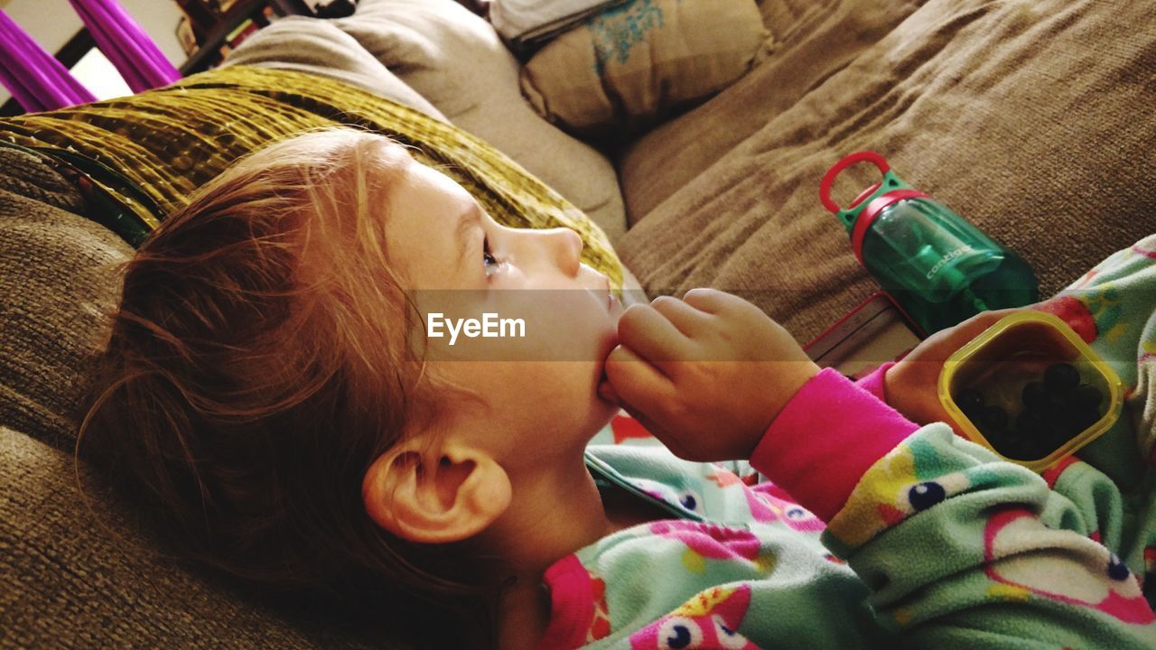 High angle view of cute baby girl relaxing on sofa at home