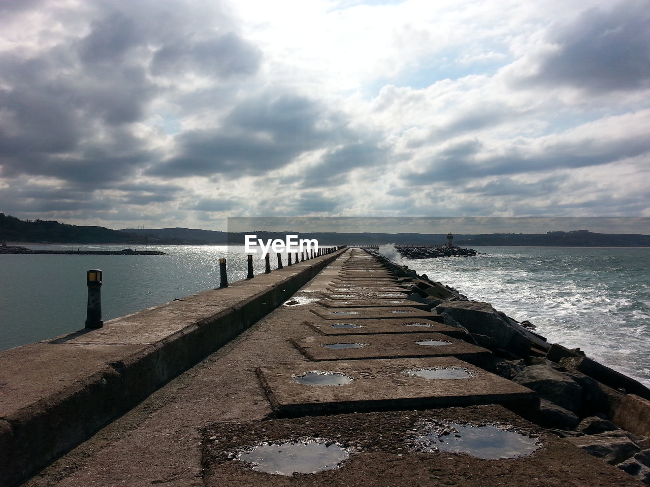 Walkway amidst sea against cloudy sky