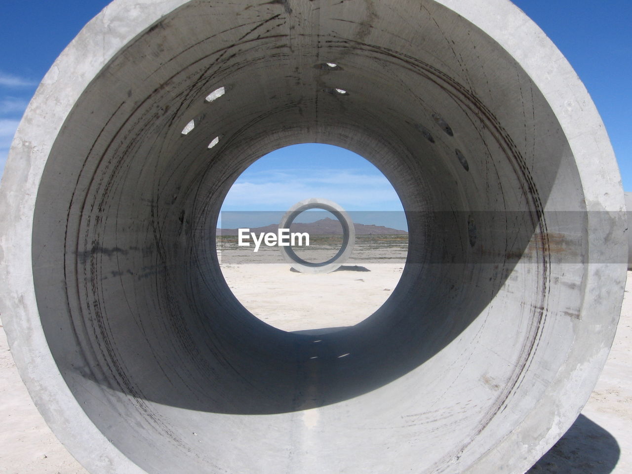 Concrete pipes on field against sky