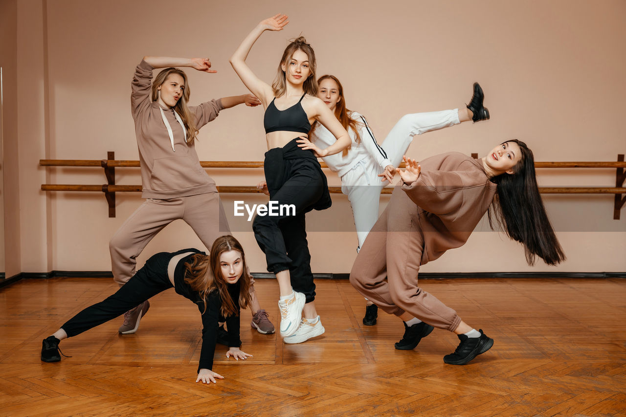 Group of girls in sportswear, performing elements of house dance in a dance studio, dancing with