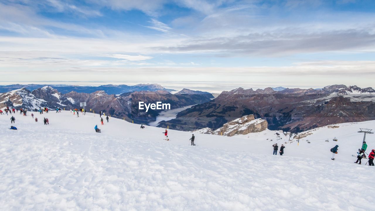 People on snow covered mountain against sky