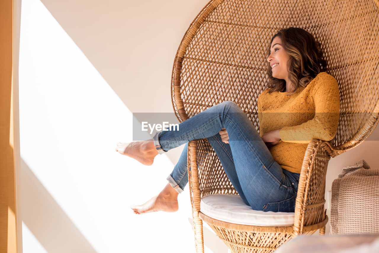 YOUNG WOMAN SITTING ON SEAT IN SHOPPING MALL