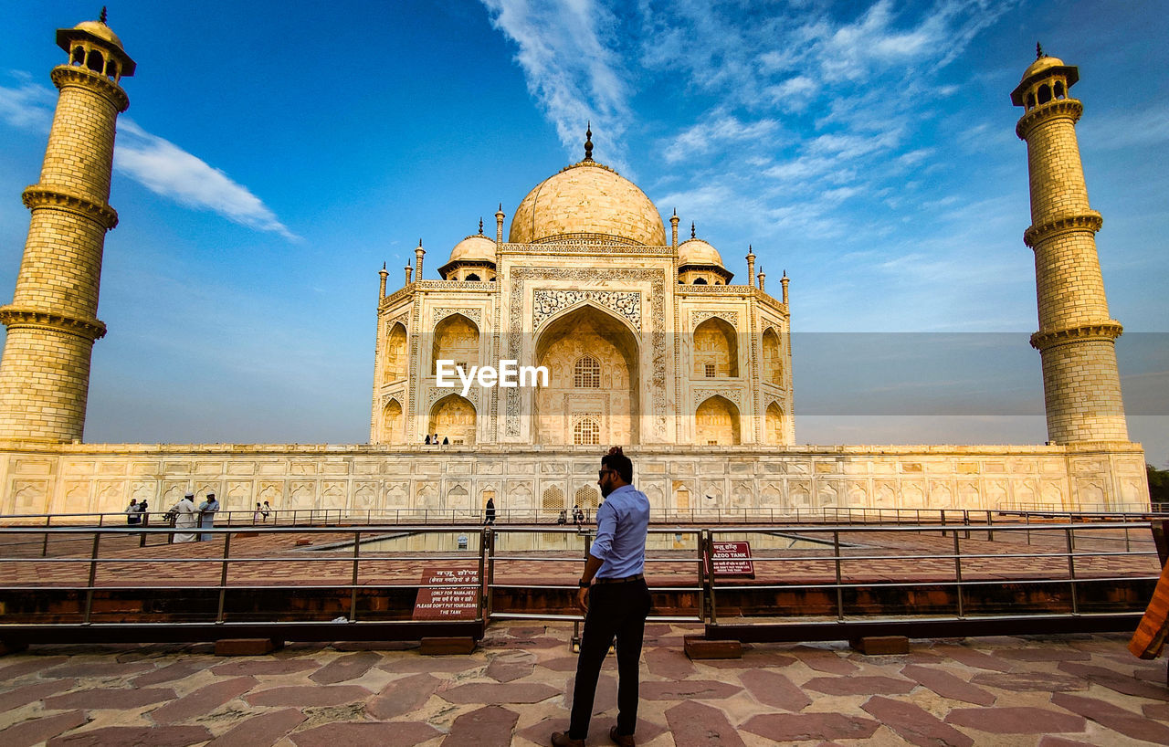 rear view of woman standing by historic building against sky