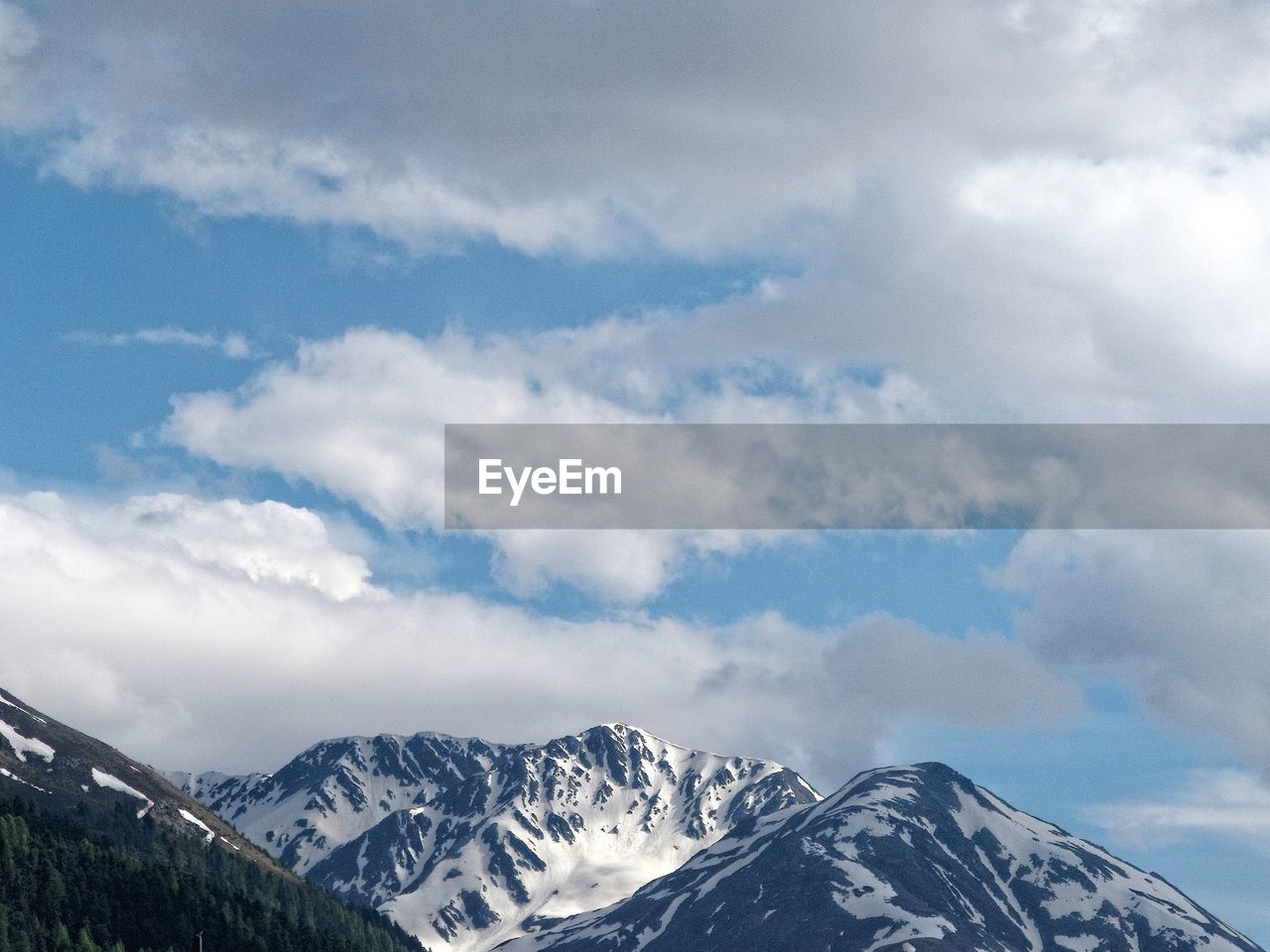 Scenic view of snow covered mountains against cloudy sky