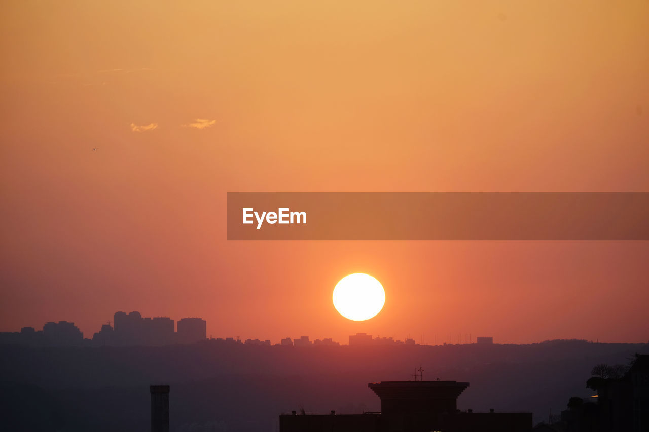 SILHOUETTE BUILDINGS AGAINST ORANGE SKY