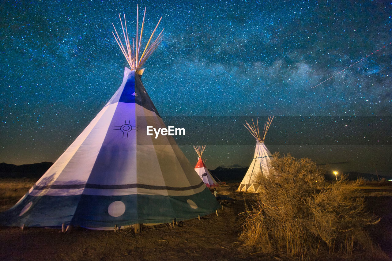 Digital composite image of tent on field against sky at night