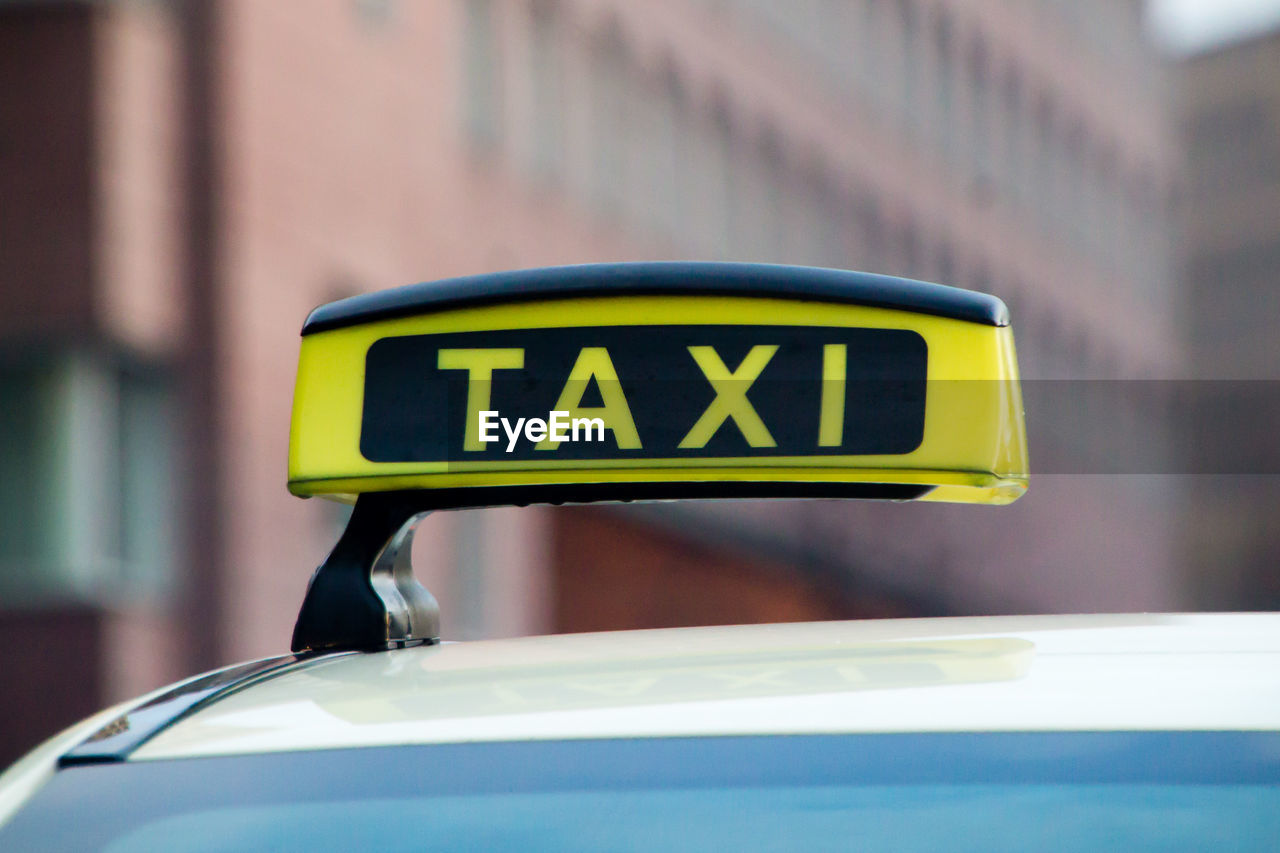 Close-up of taxi sign against building