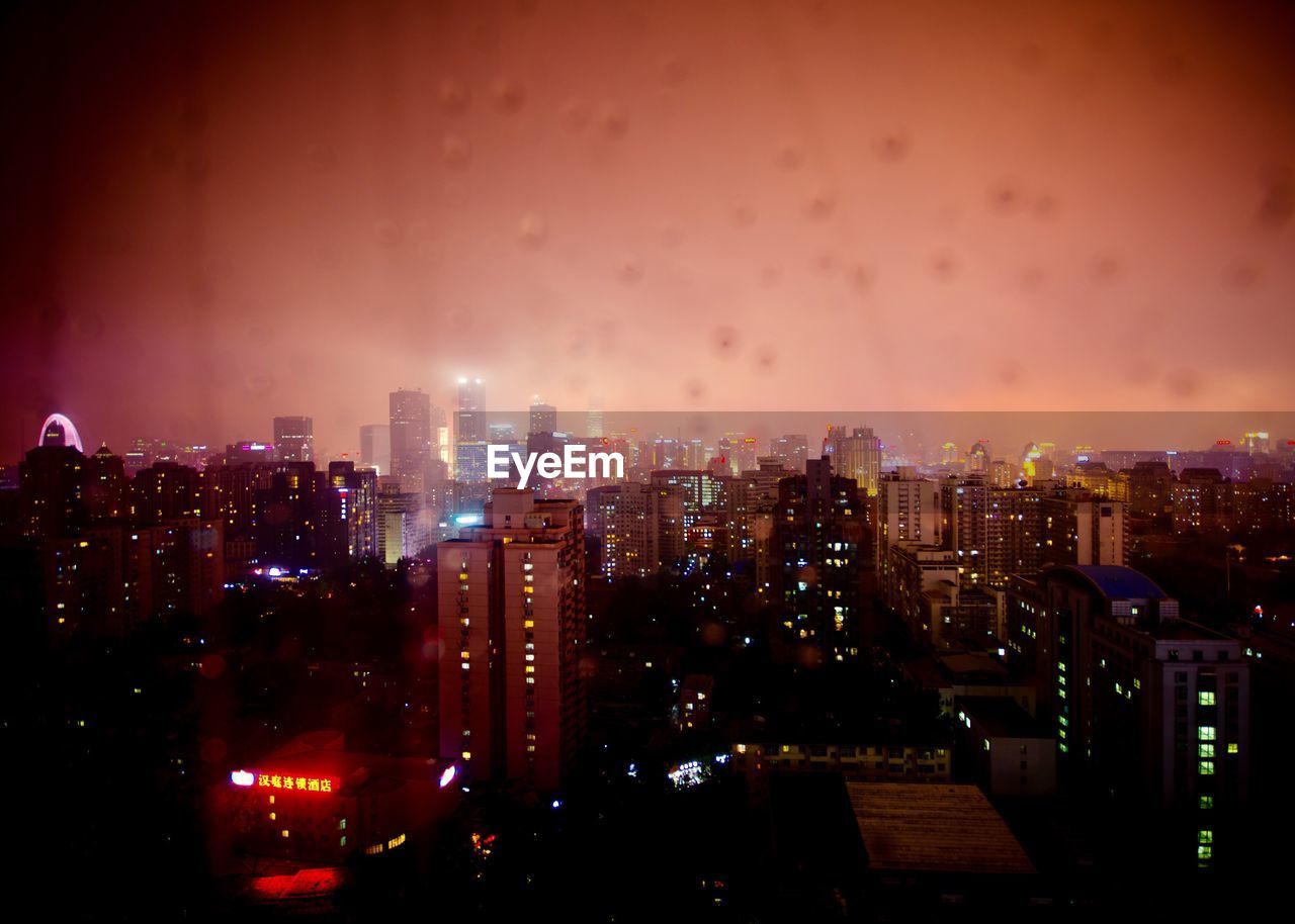 Illuminated cityscape against sky at night