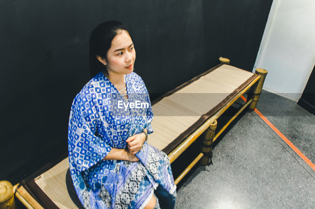 High angle view of woman looking away while sitting on bench