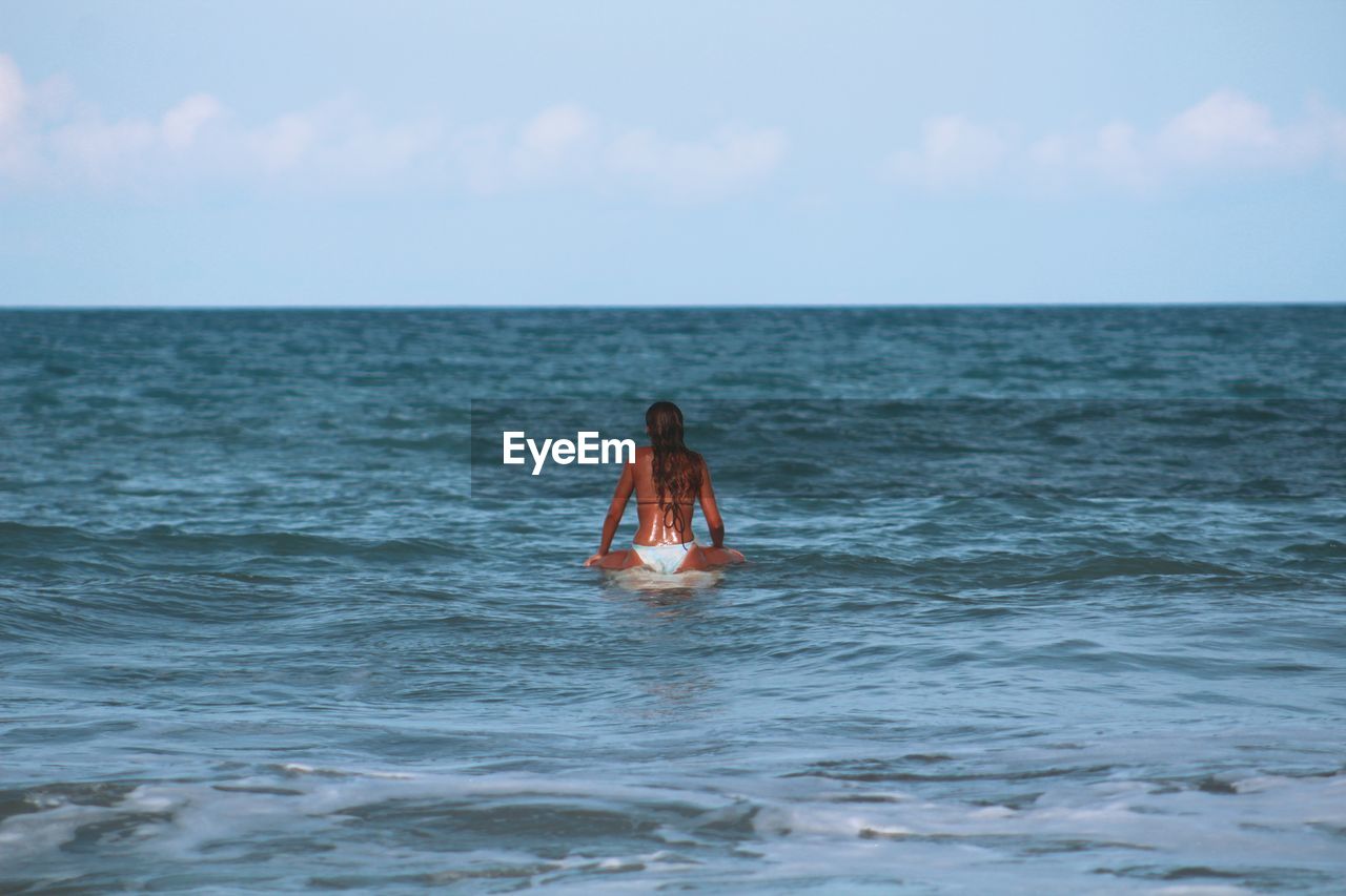 Woman in sea against sky