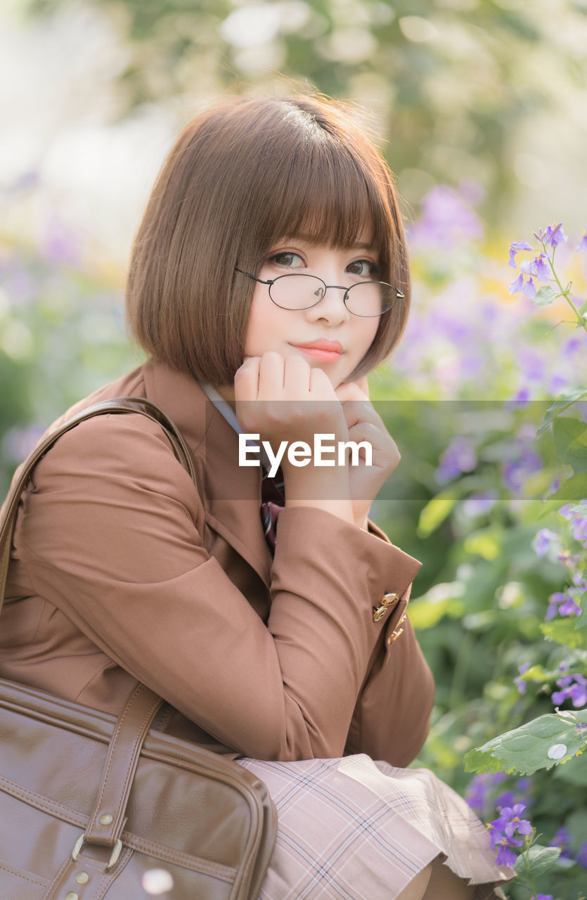 Portrait of woman sitting by plants at park