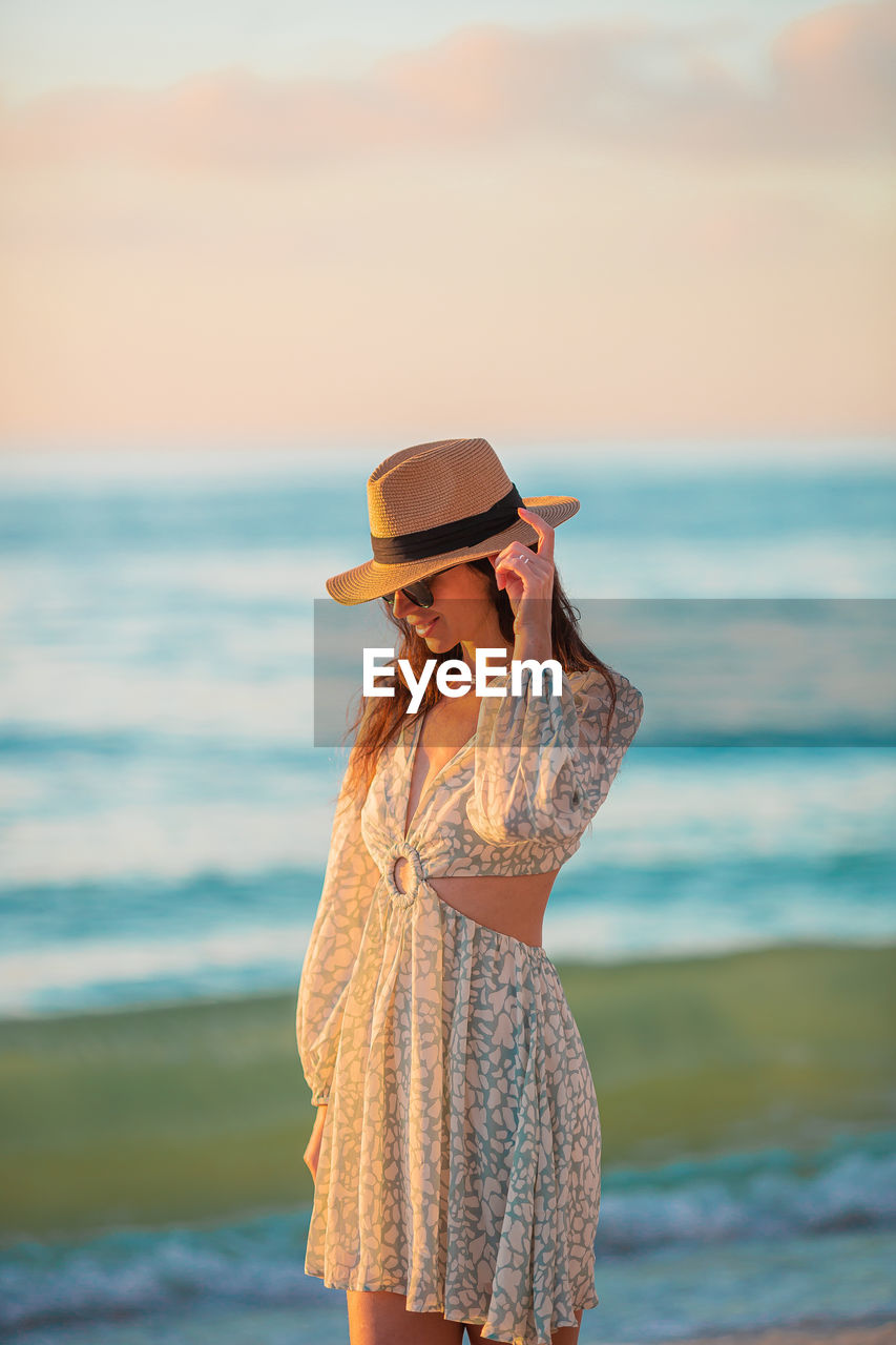 rear view of woman standing at beach against sky