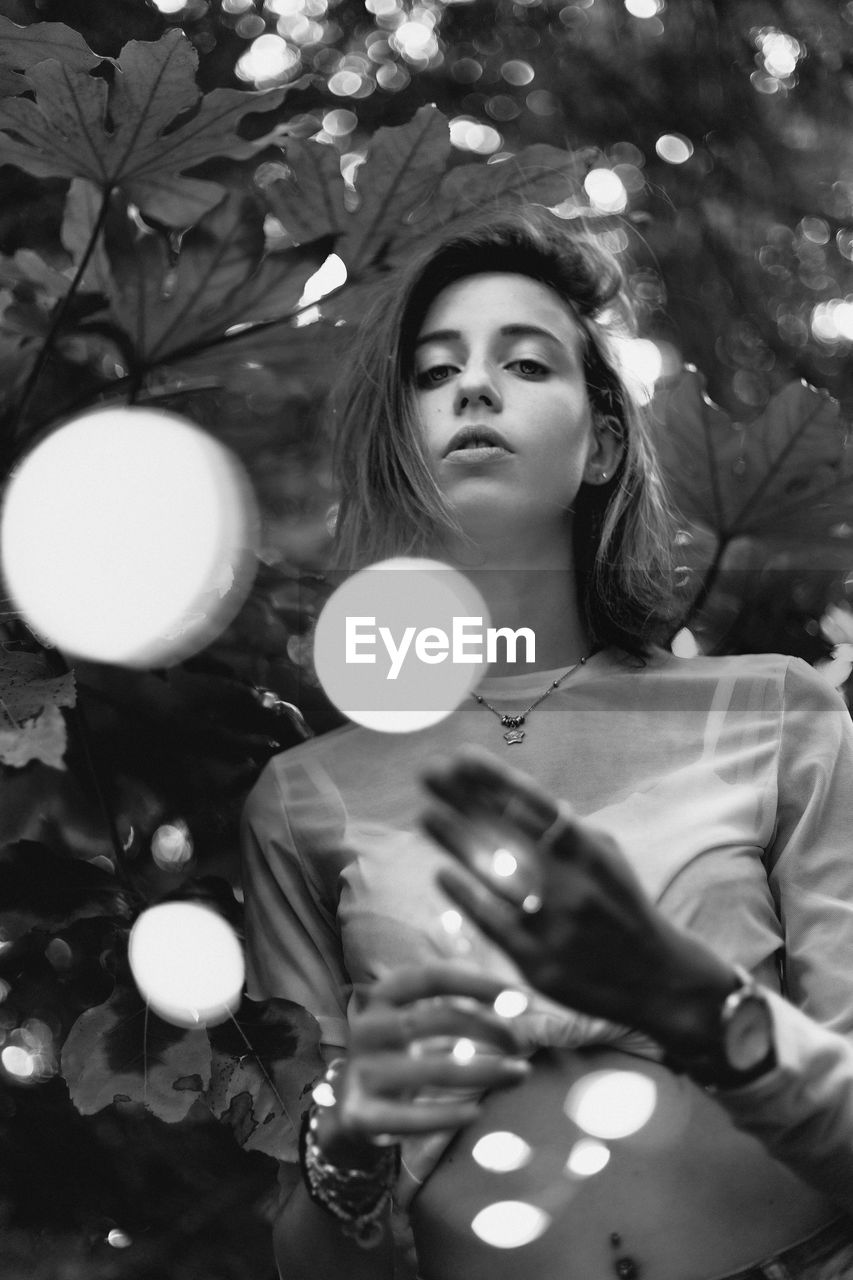 PORTRAIT OF YOUNG WOMAN LOOKING AWAY IN TREE