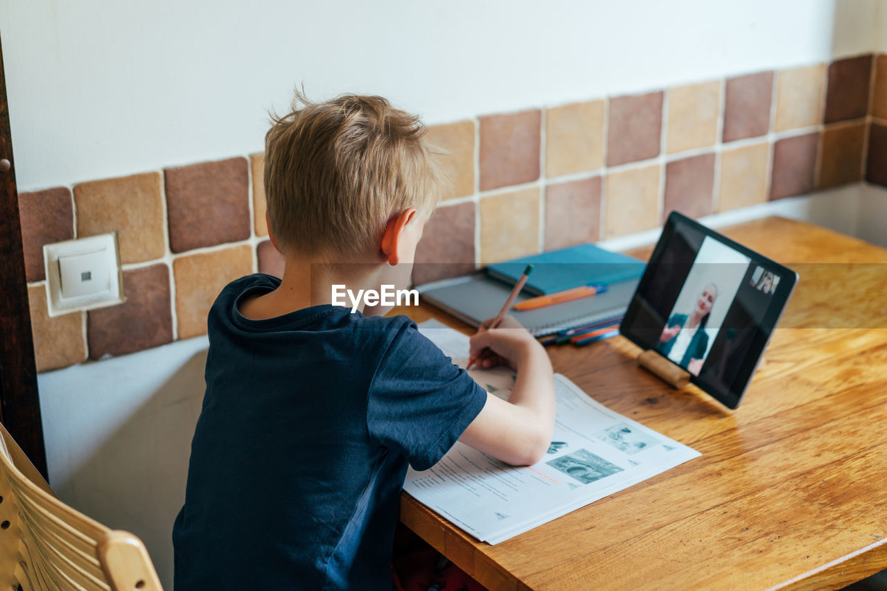 Rear view of boy studying at home