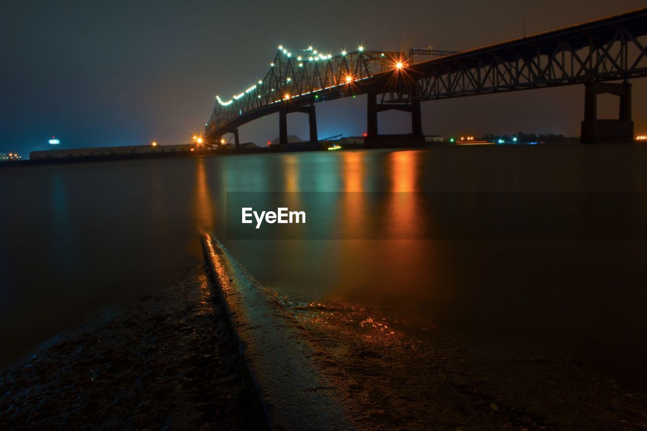 SUSPENSION BRIDGE OVER RIVER AT NIGHT