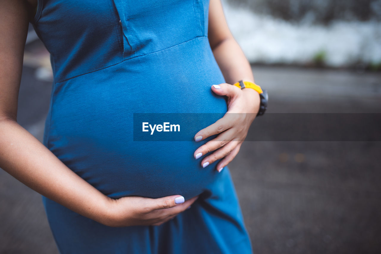 Midsection of pregnant woman standing outdoors