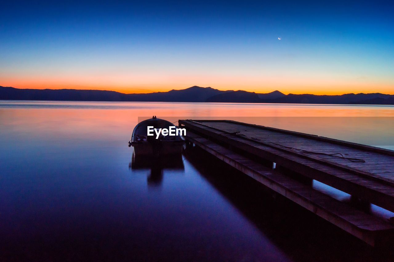 Lone boat moored at jetty in calm lake