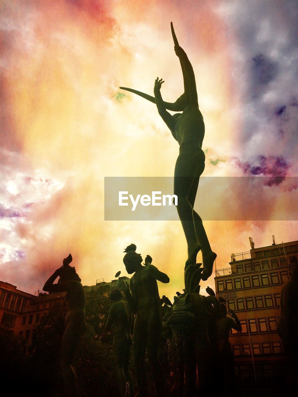 LOW ANGLE VIEW OF STATUE AGAINST CLOUDY SKY AT SUNSET