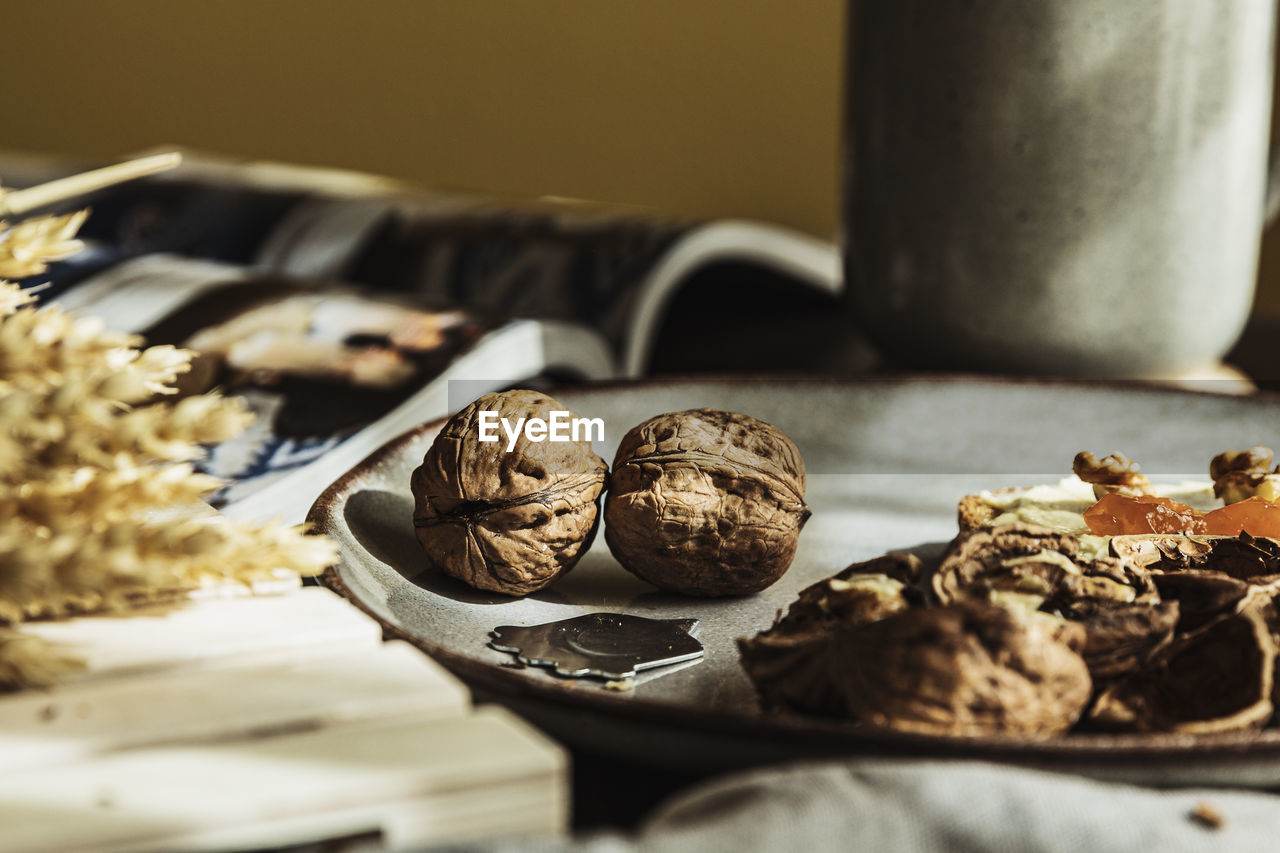 Beautiful walnuts and a nutpick on a plate in a cozy wooden table