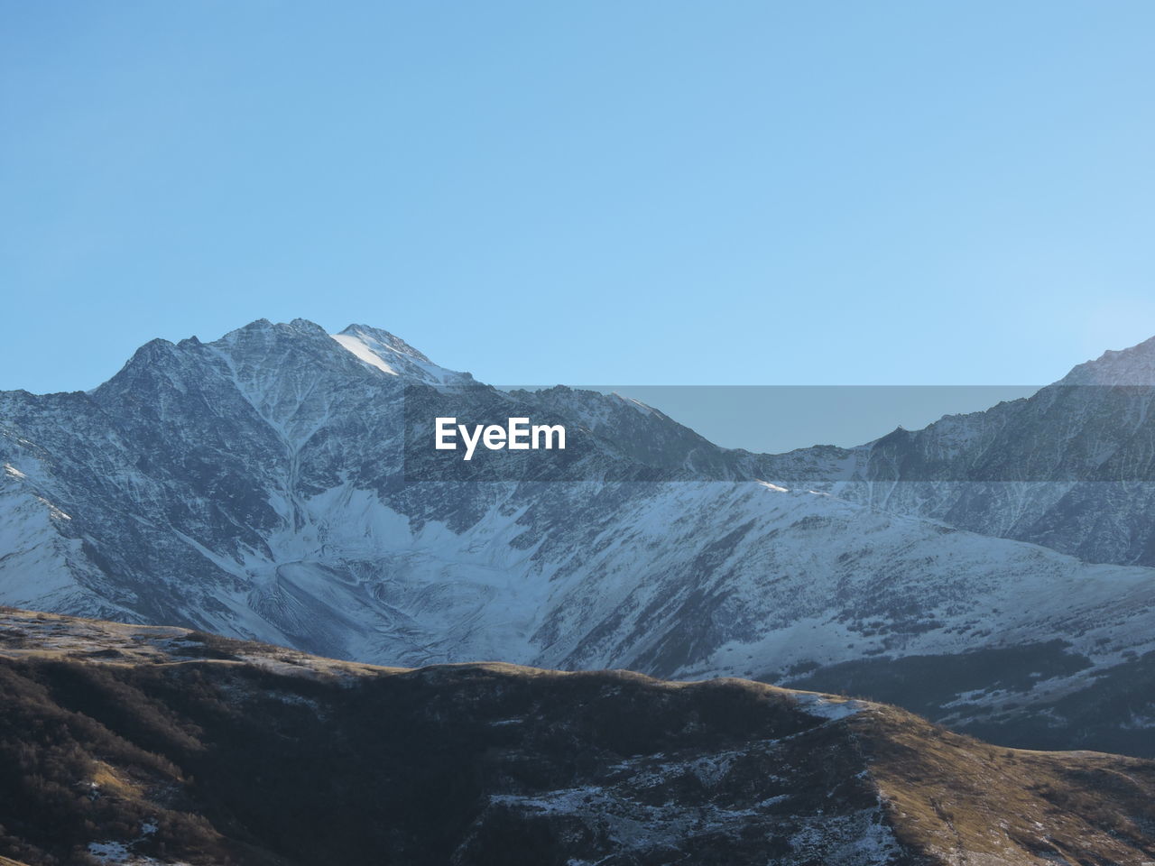 Scenic view of snowcapped mountains against clear blue sky