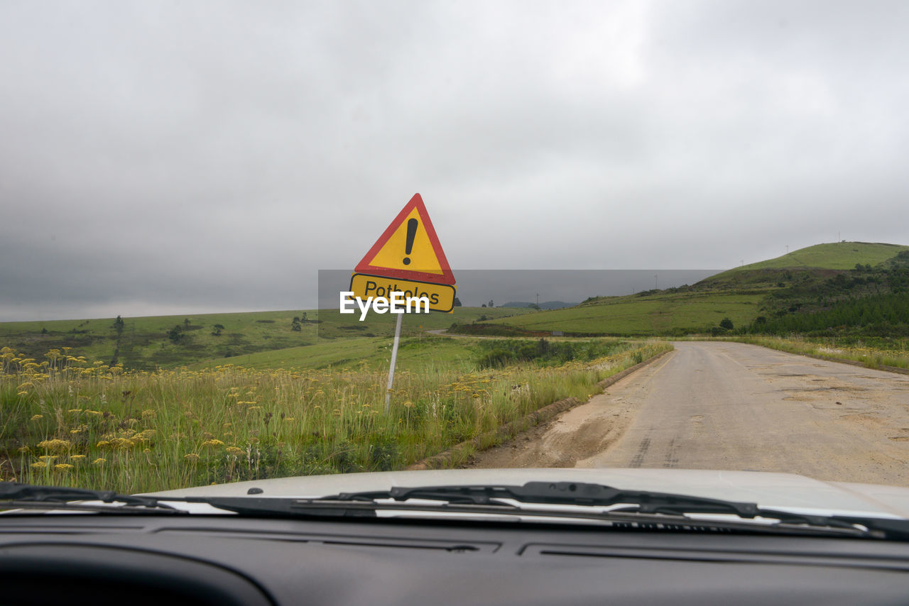 ROAD SIGN IN CAR AGAINST SKY