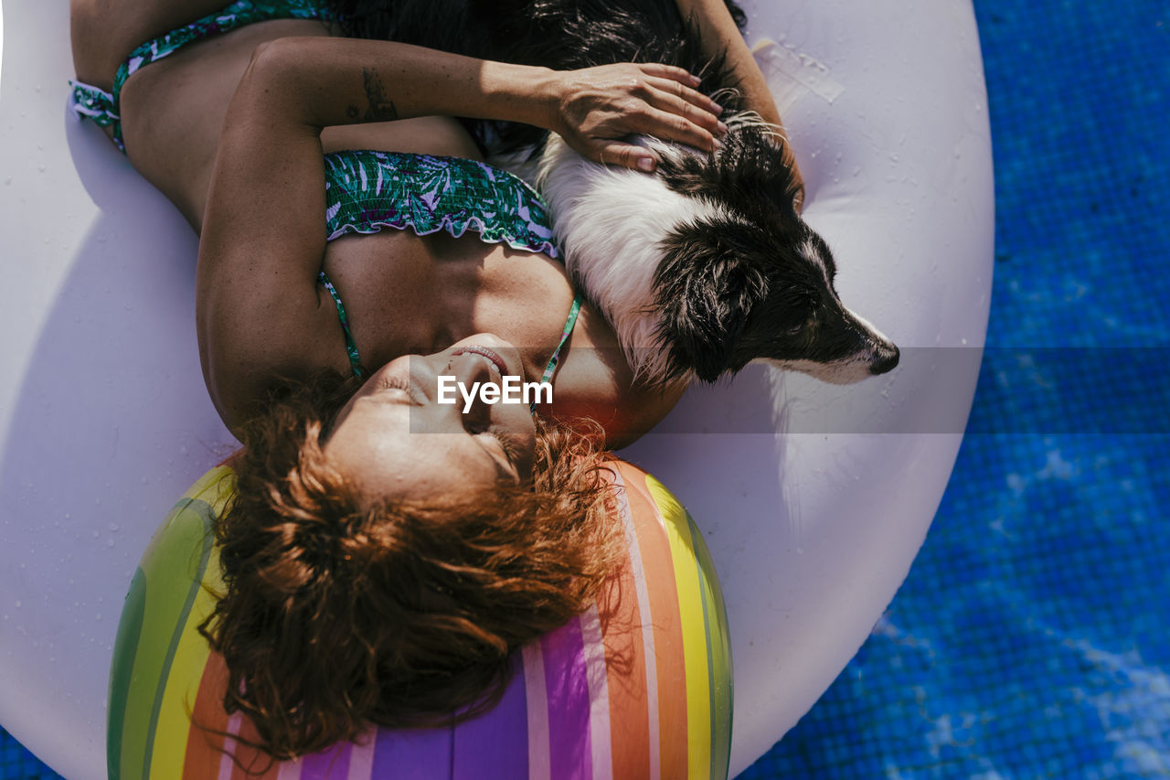 High angle view of woman with dog on inflatable ring in swimming pool