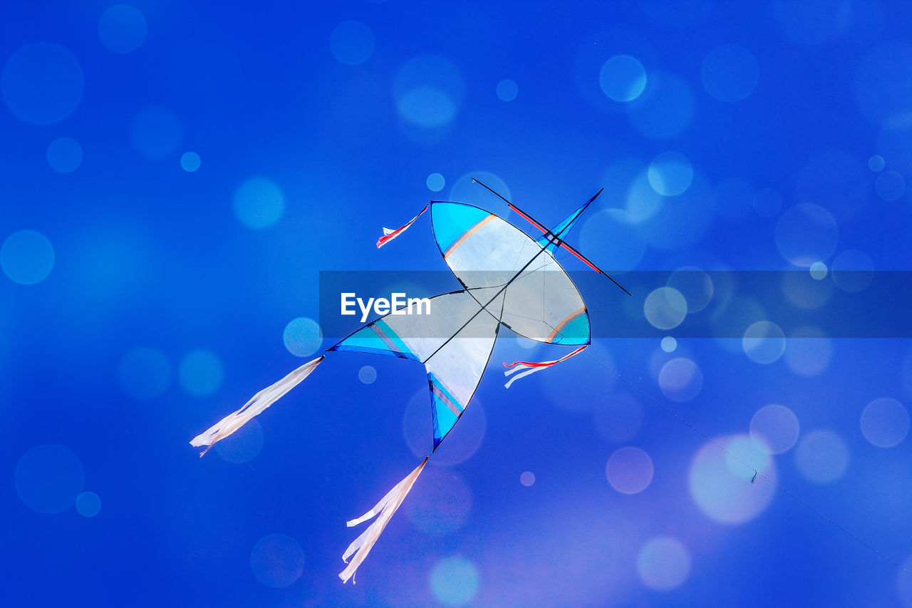 Low angle view of kite flying against clear blue sky