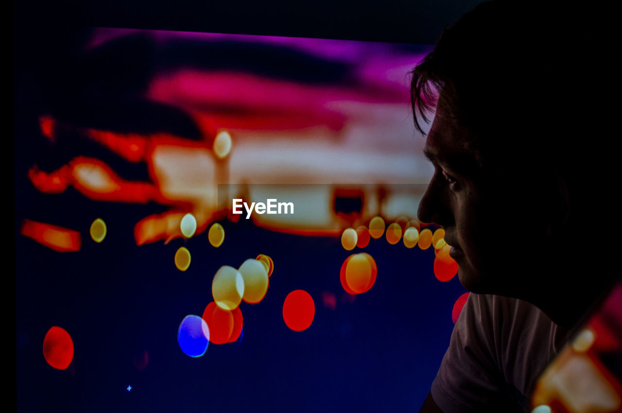 Close-up portrait of boy looking at illuminated lights