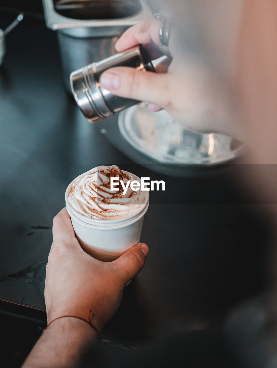 Barista preparing a delicious cinnamon espresso coffee on small white cup. cinnamon on top of cream