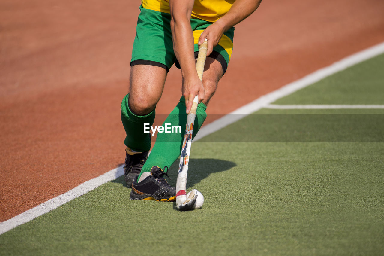 Low section of man playing hockey on playing field