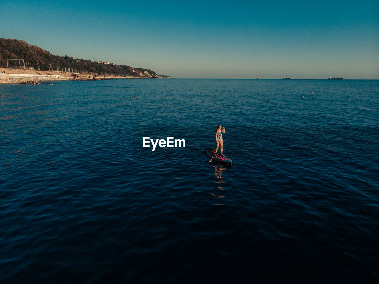 Full length of woman paddleboarding in sea