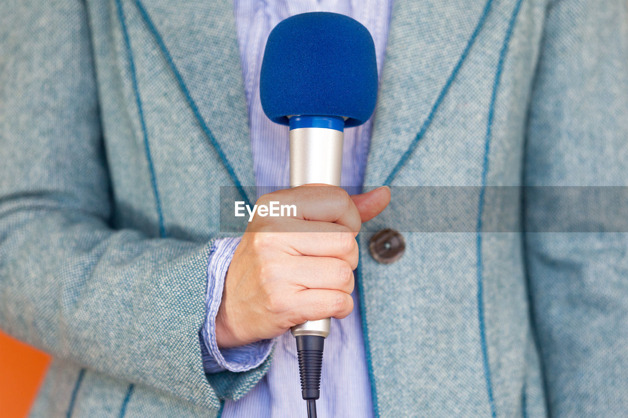 Midsection of man holding microphone