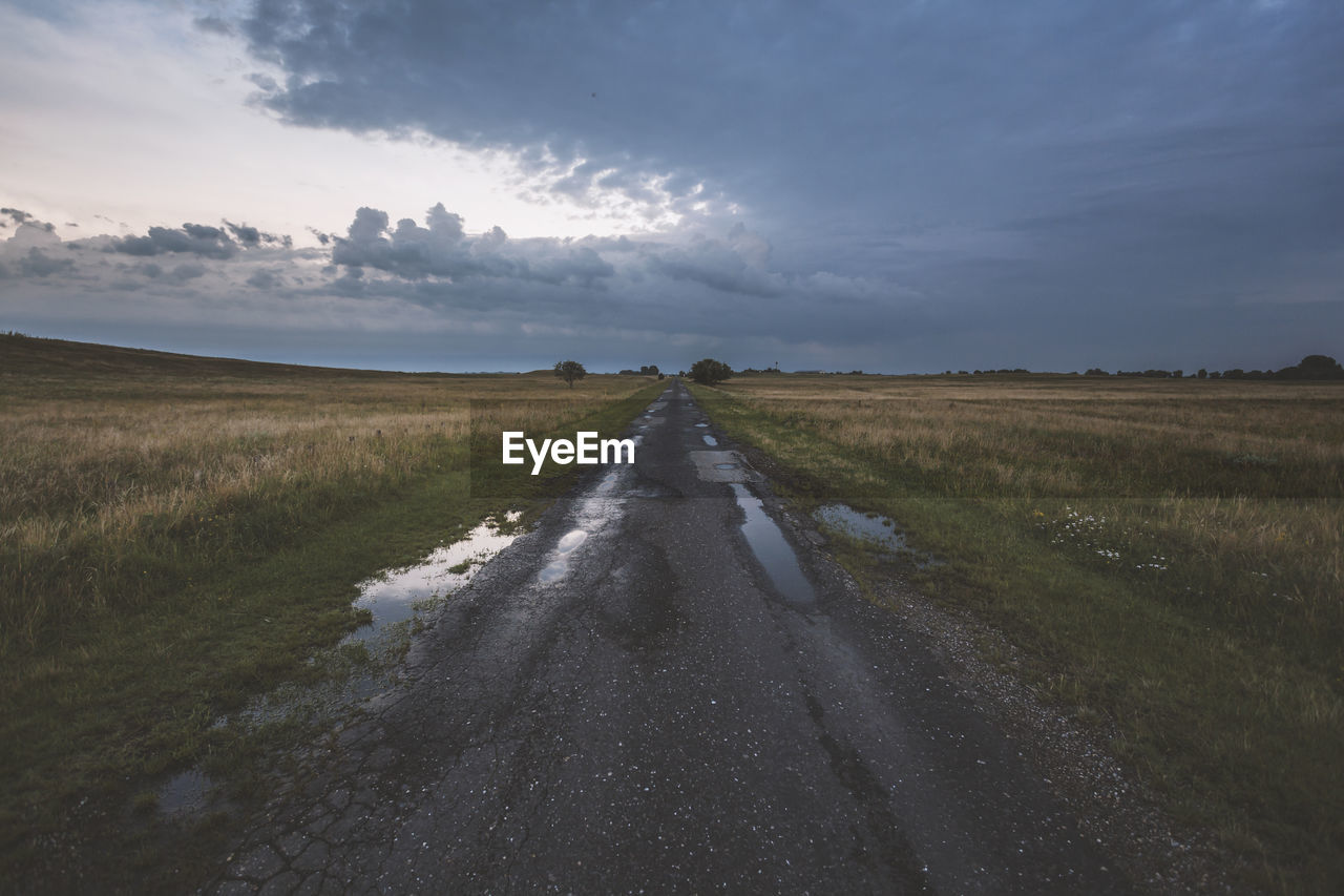 Road amidst field against sky