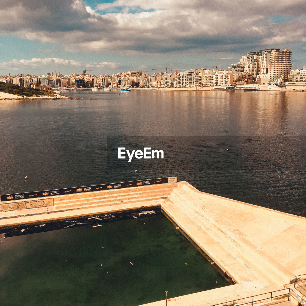 HIGH ANGLE VIEW OF RIVER AMIDST BUILDINGS AGAINST SKY