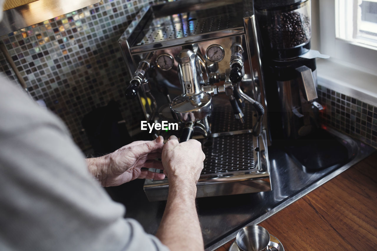 Cropped image of hand holding coffee filter using espresso maker at home