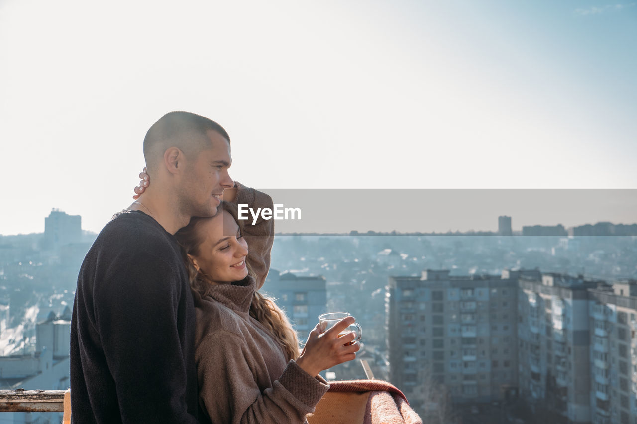 Young couple drinking coffee on the balcony of the apartment in the morning. young happy couple