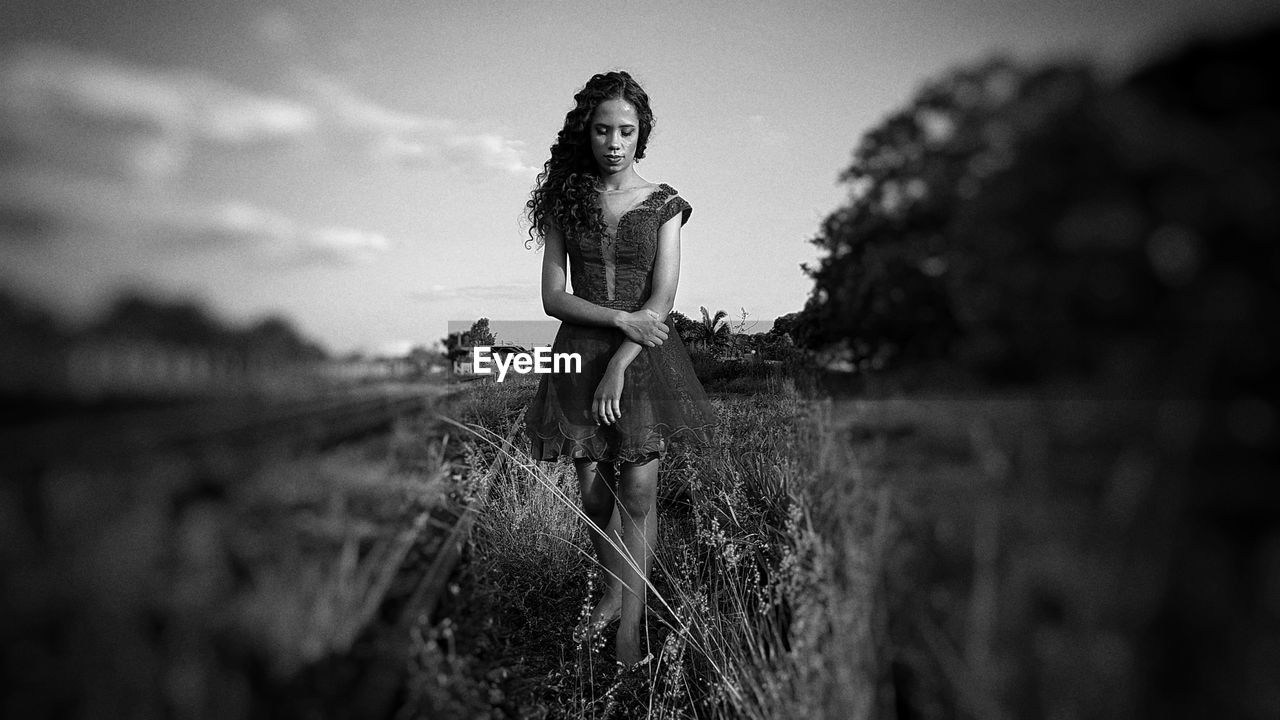 Young woman walking on field against sky