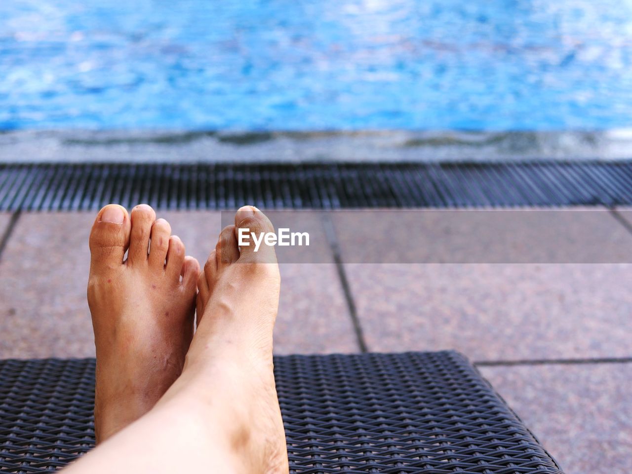 Low section of person resting at poolside