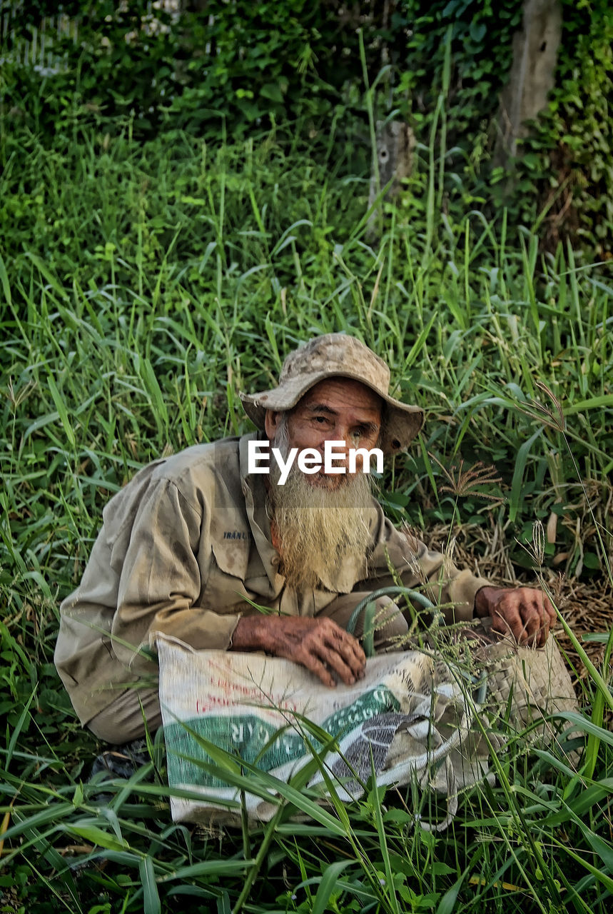 PORTRAIT OF MAN SITTING ON FIELD